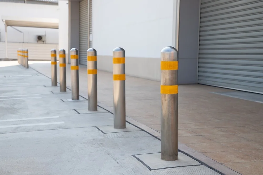 steel bollards with yellow reflex strip near footpath in front of the shutter door.